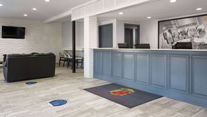 A reception area with a counter, seating, and a wall-mounted TV. - Super 8 by Wyndham Universal City (Universal City)