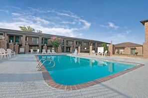 Un hotel con piscina, mobiliario exterior y fachada de ladrillo.