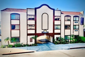 A Days Inn with a central archway, multiple windows, and a parking area. - Days Inn by Wyndham Alhambra CA (Alhambra)