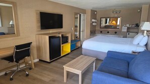 Une chambre d’hôtel comprenant un lit, une télévision, un bureau, une chaise, une petite table et un canapé.