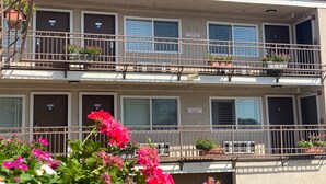Un immeuble à plusieurs étages doté de balcons, chacun ayant une petite table et des plantes en pot.