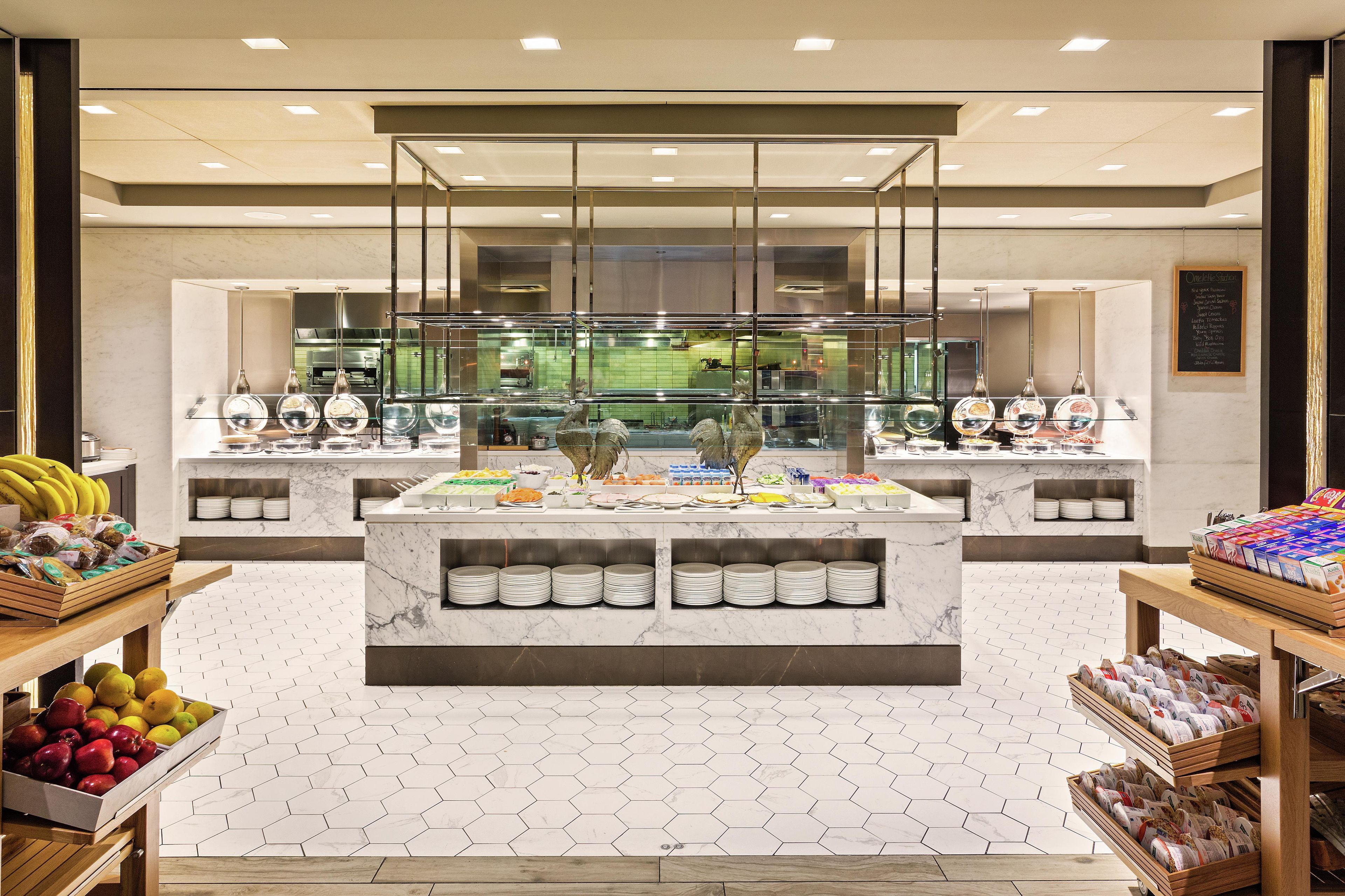 A buffet area with a marble countertop, glassware, and a variety of food items.