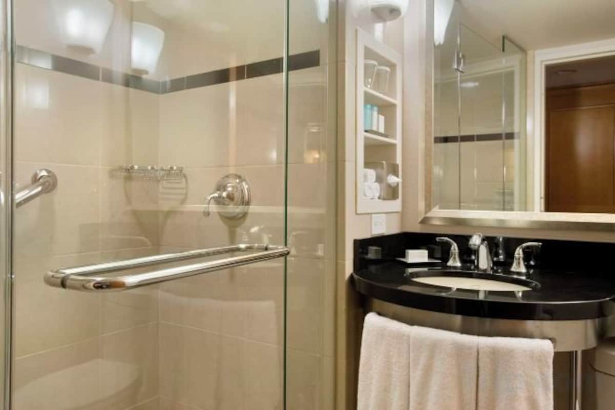 A modern bathroom with a glass shower enclosure, a black sink, and a mirror above it.