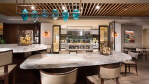 A modern dining area with marble tables, wooden chairs, and a central island with a decorative vase.