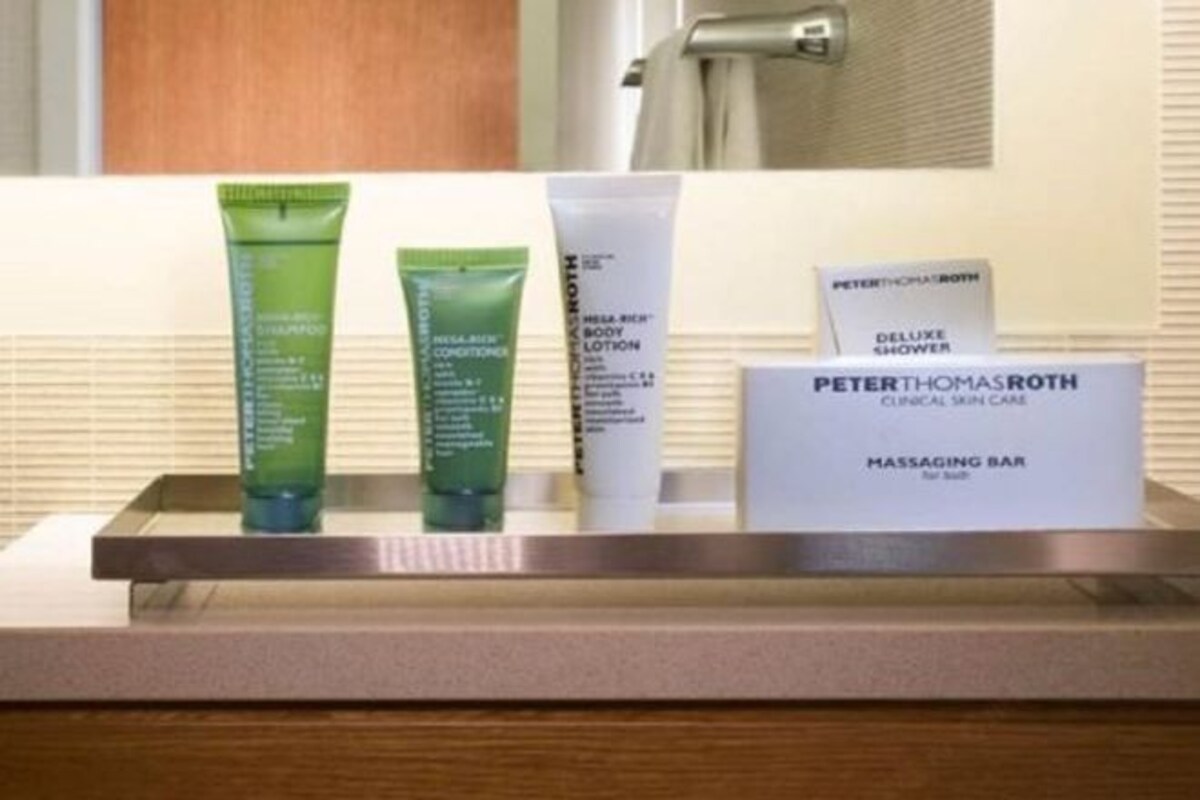 A bathroom counter with various Peter Thomas Roth products including a body lotion, a body conditioner, and a clinical skin care bar.