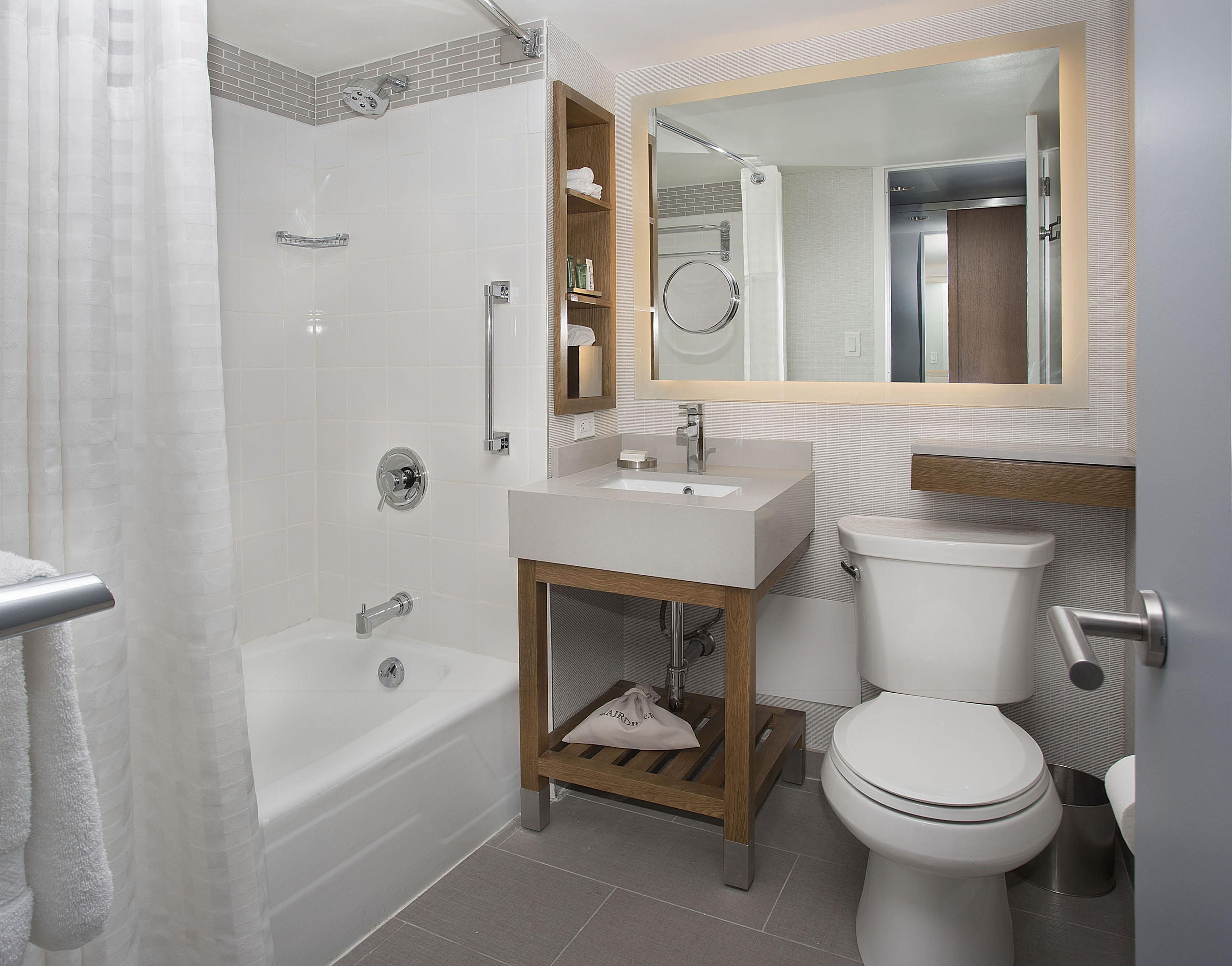 A modern bathroom with a bathtub, a sink, a toilet, and a mirror.