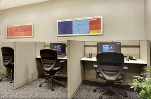 A cubicle office with two desks, each with a computer and a chair.