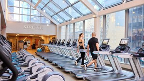 A gym with treadmills, a mirrored wall, and a skylight.