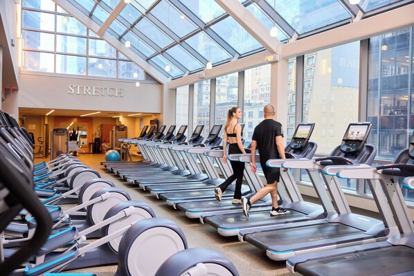 A gym with treadmills, a mirrored wall, and a skylight.