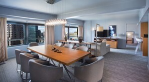 Een moderne hotelkamer met een zithoek, een woongedeelte met een televisie en uitzicht op de stad.