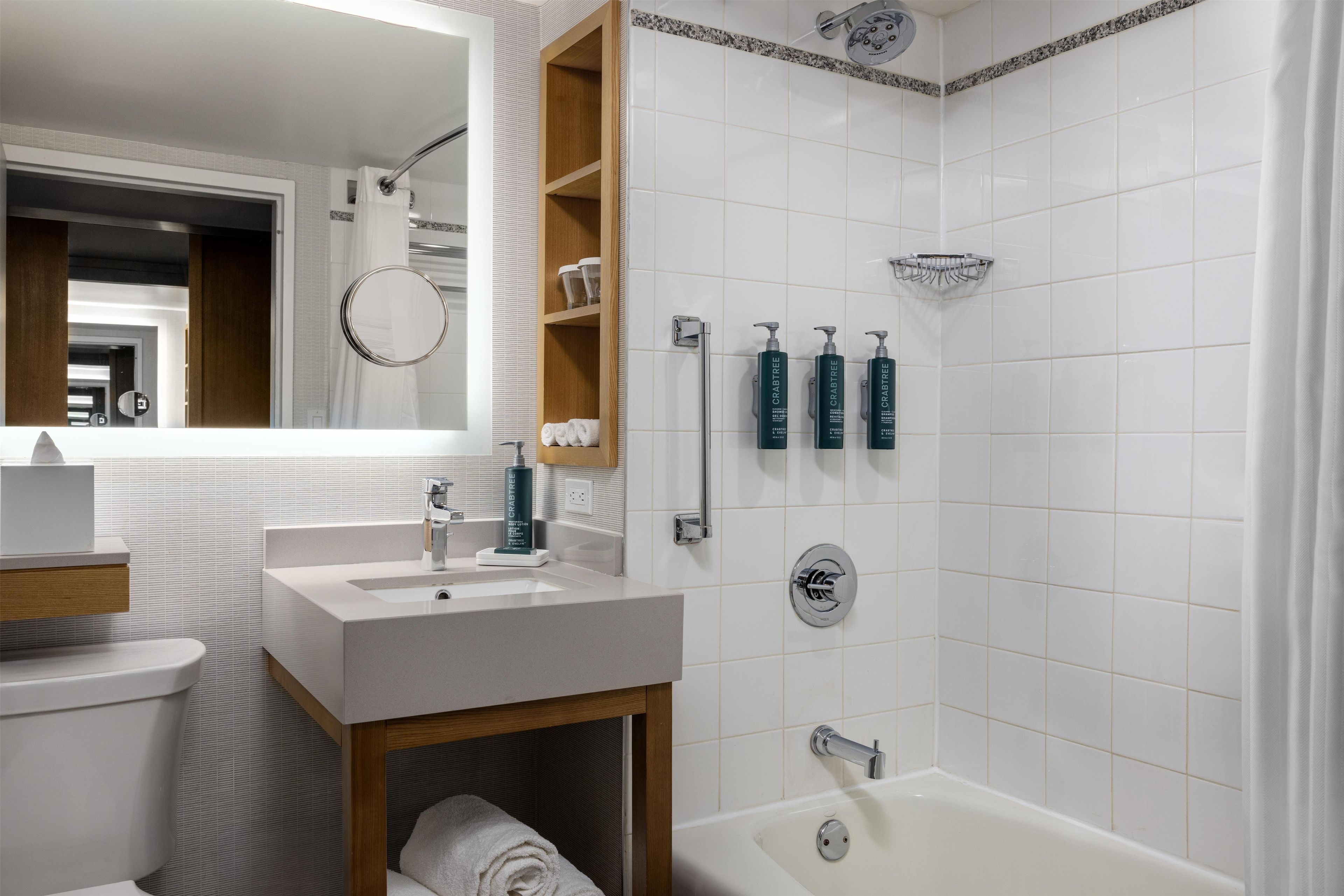 A modern bathroom with a white sink, mirror, and a shower area.