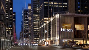 A hotel with a prominent Hilton sign, modern architecture, and a city street at dusk.