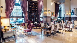 A spacious lobby with a seating area, a fireplace, and a large bookshelf. - The Culver Hotel (Culver City)