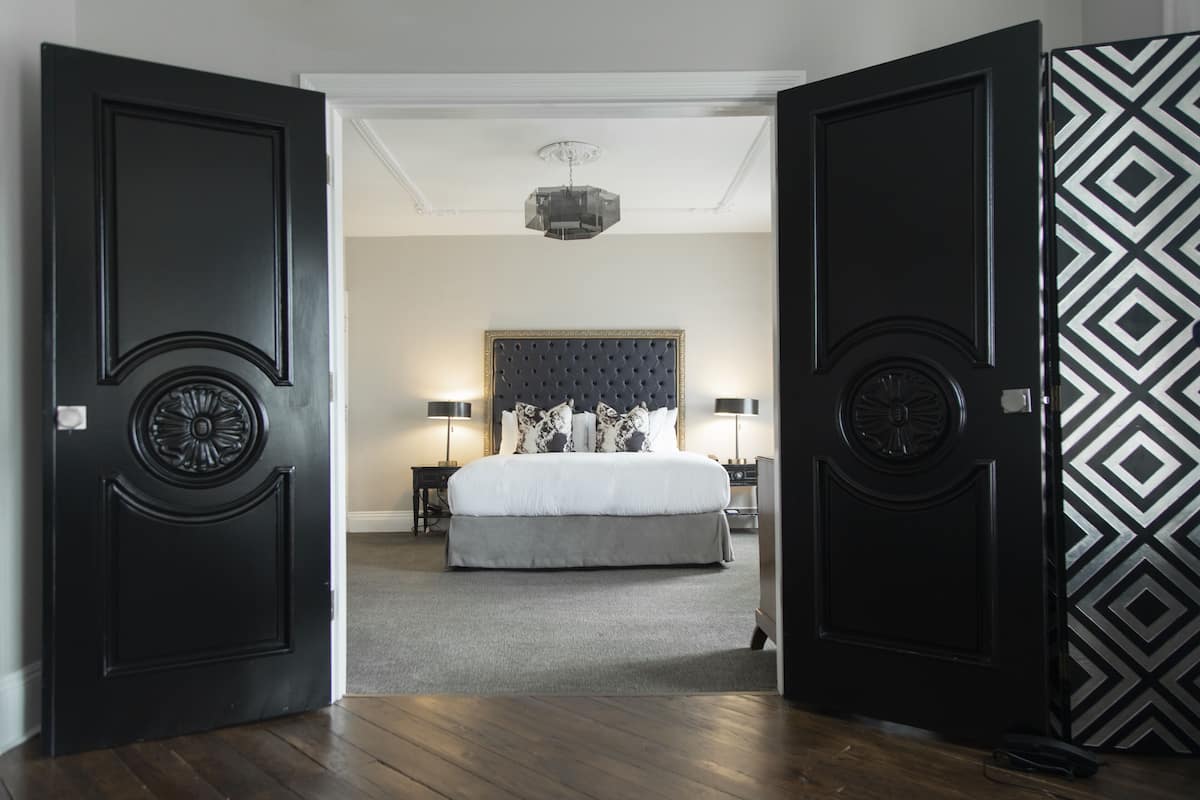A bedroom with a large bed, a headboard, bedside tables, and a chandelier.