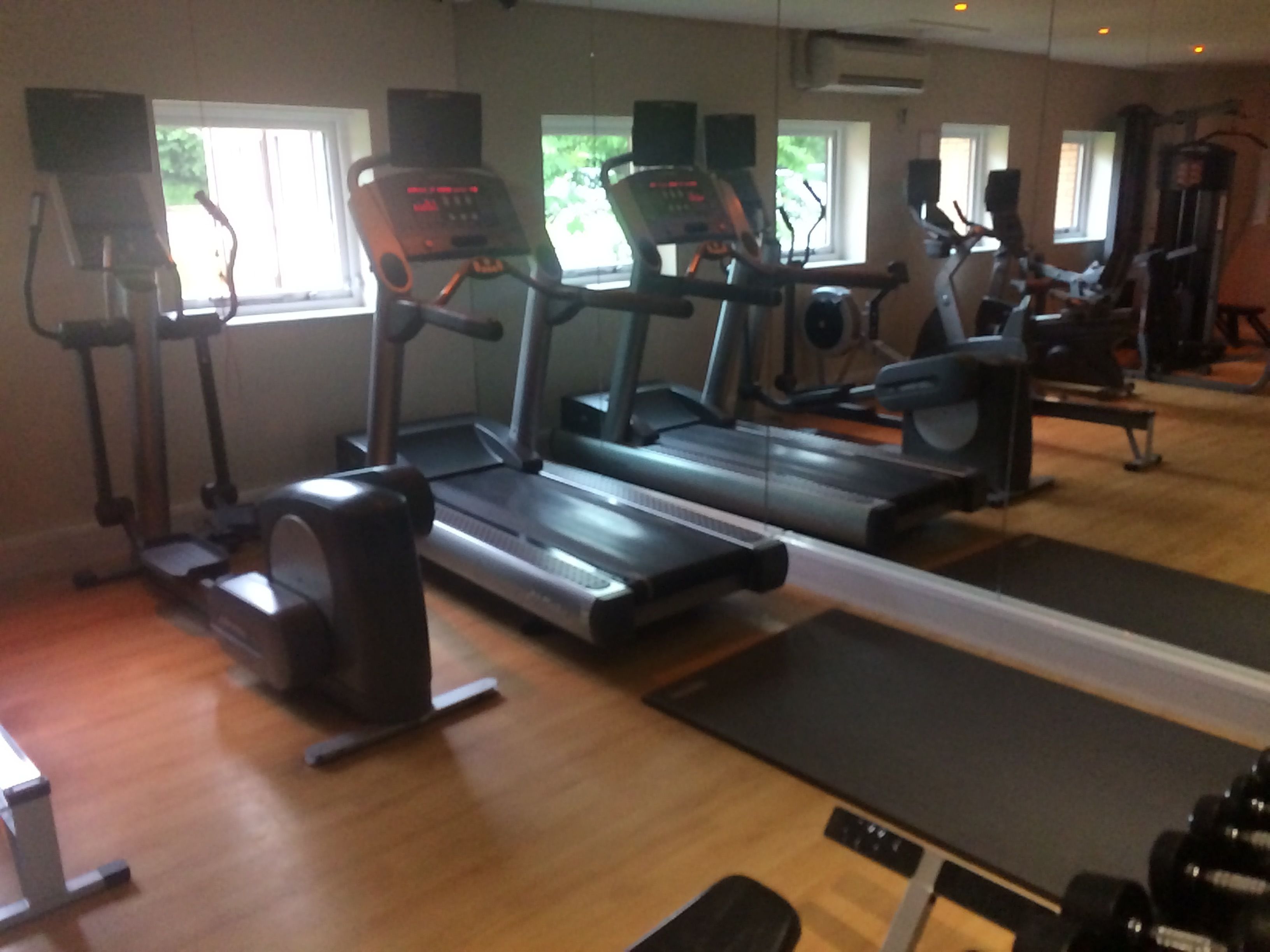 Un gimnasio con cintas de correr, elípticas y equipo de pesas.