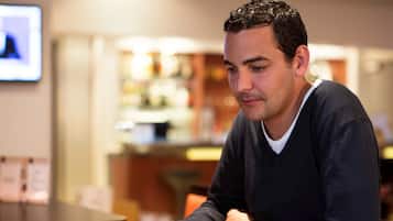 A person reading a newspaper at a table in a cafe.