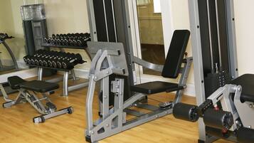 Un gimnasio con diversos equipos de ejercicio, como mancuernas, bancos y máquinas de pesas.