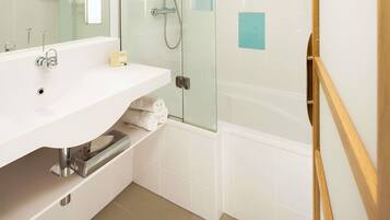 A modern bathroom with a white sink, mirror, and glass shower enclosure.