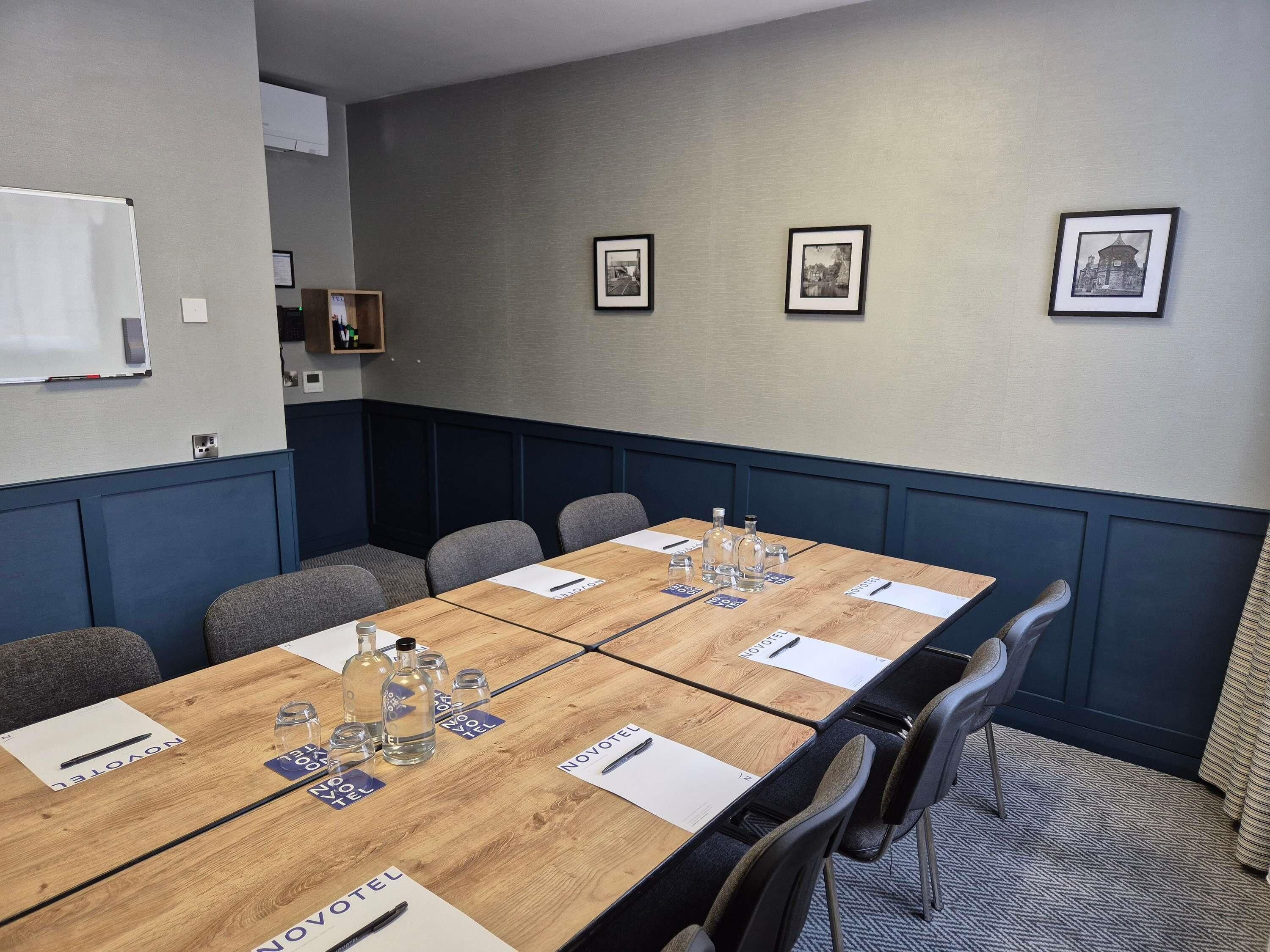 A conference room with a long table, chairs, name cards, and framed pictures on the wall.