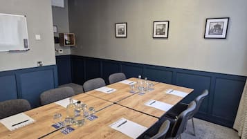 A conference room with a long table, chairs, name cards, and framed pictures on the wall.