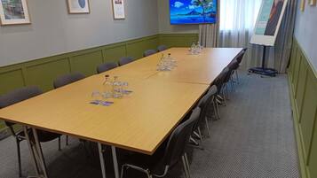 A conference room with a long table, chairs, a TV, framed certificates, and a projector screen.