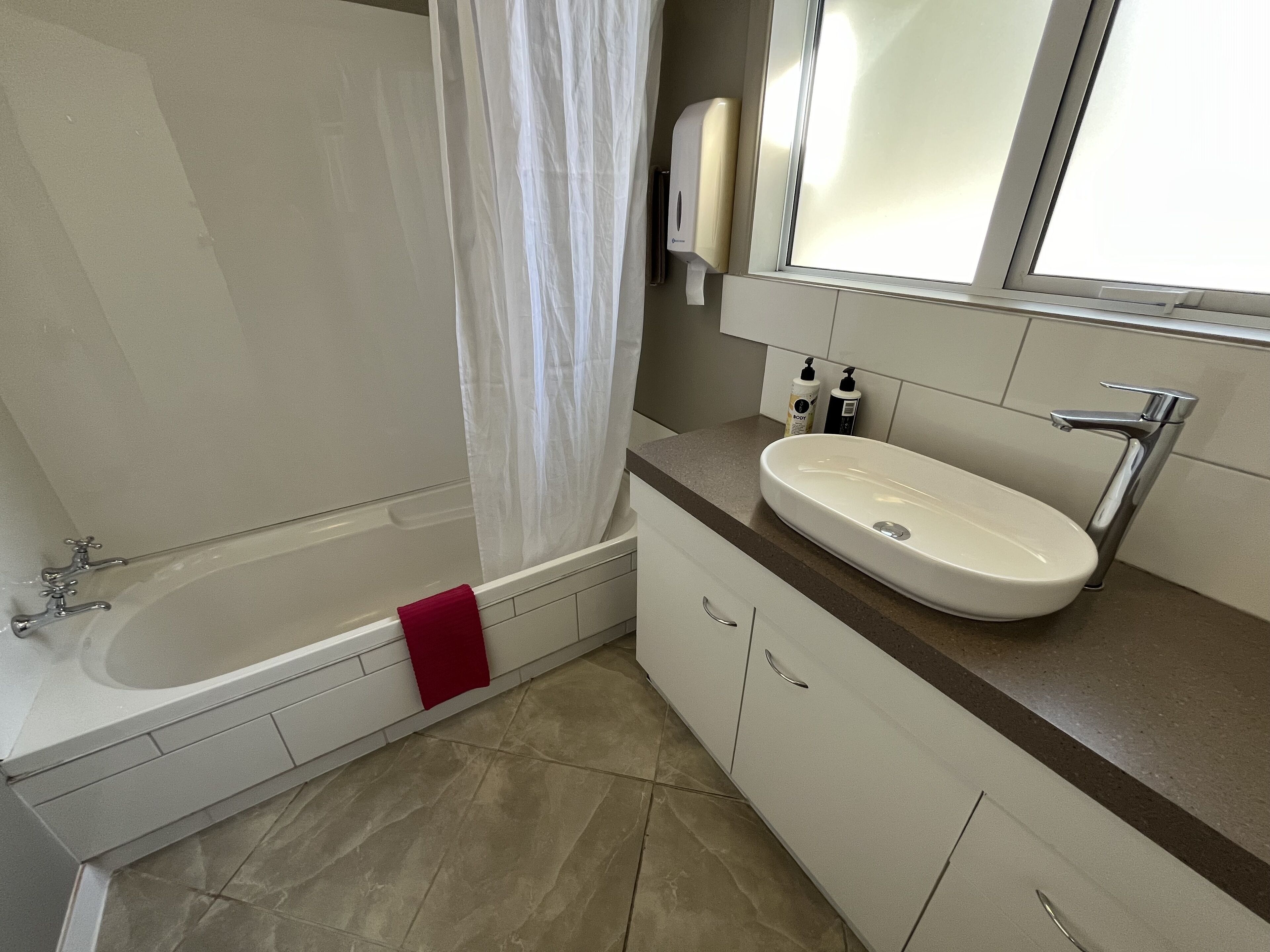 Un baño moderno con bañera, lavamanos y cortina de ducha.