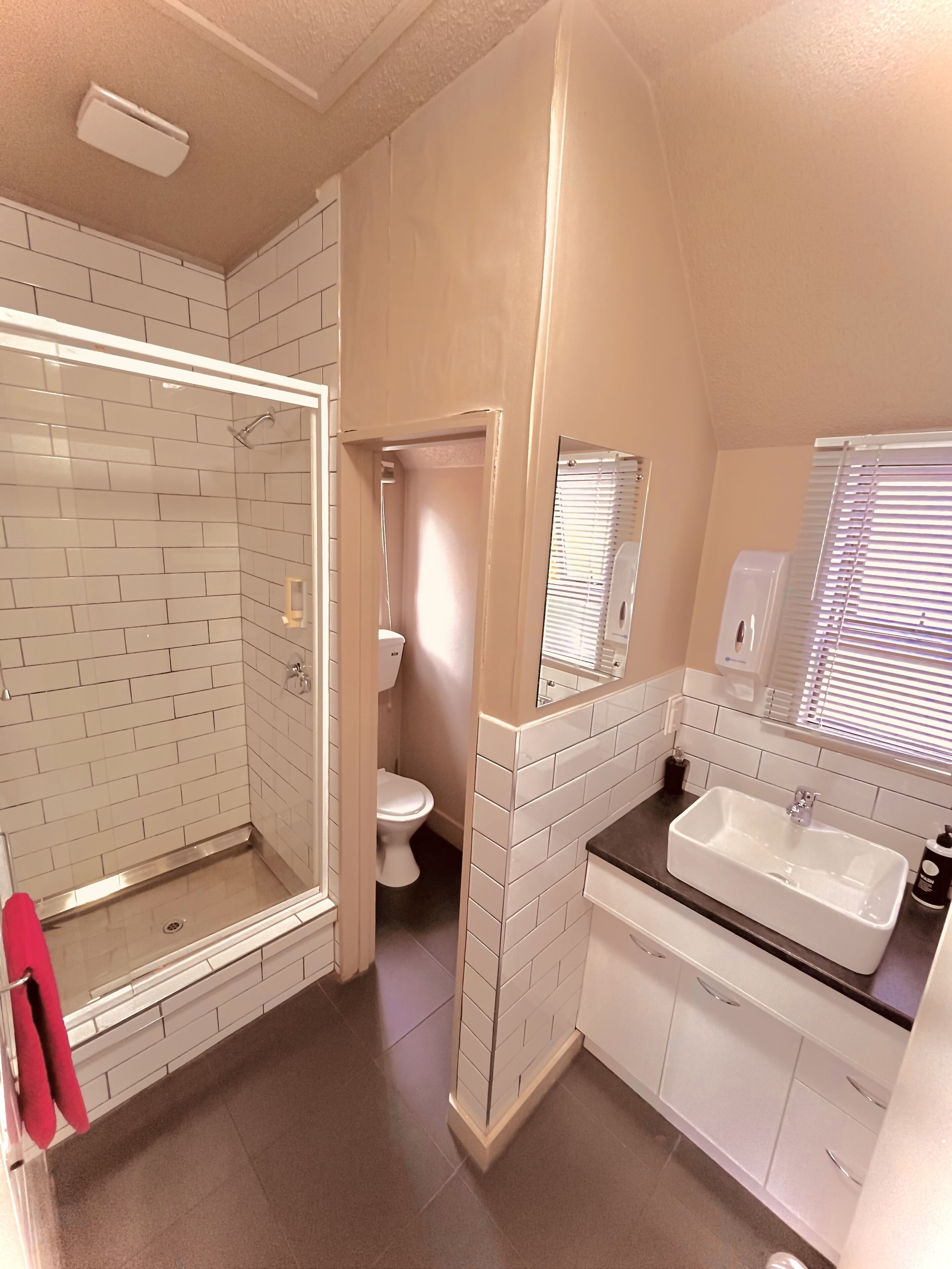 A bathroom with a shower, toilet, sink, and mirror.
