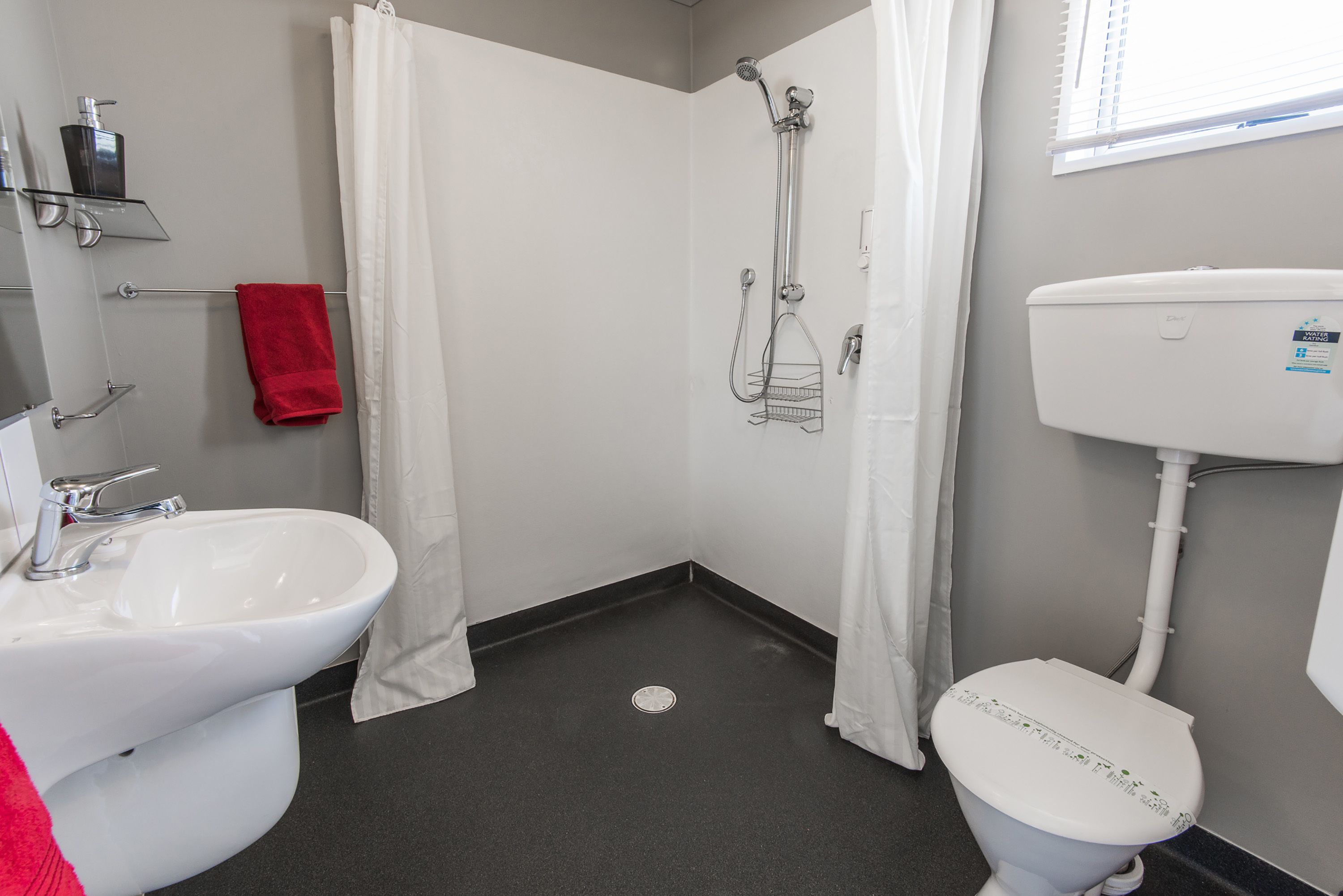 Un baño con lavamanos, inodoro y ducha blancos.