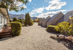 Une allée de gravier mène à une rangée de maisons modernes de plain-pied, avec une chaîne de montagnes en toile de fond.