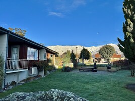Un barrio residencial con una casa, un césped cuidado y una montaña al fondo.