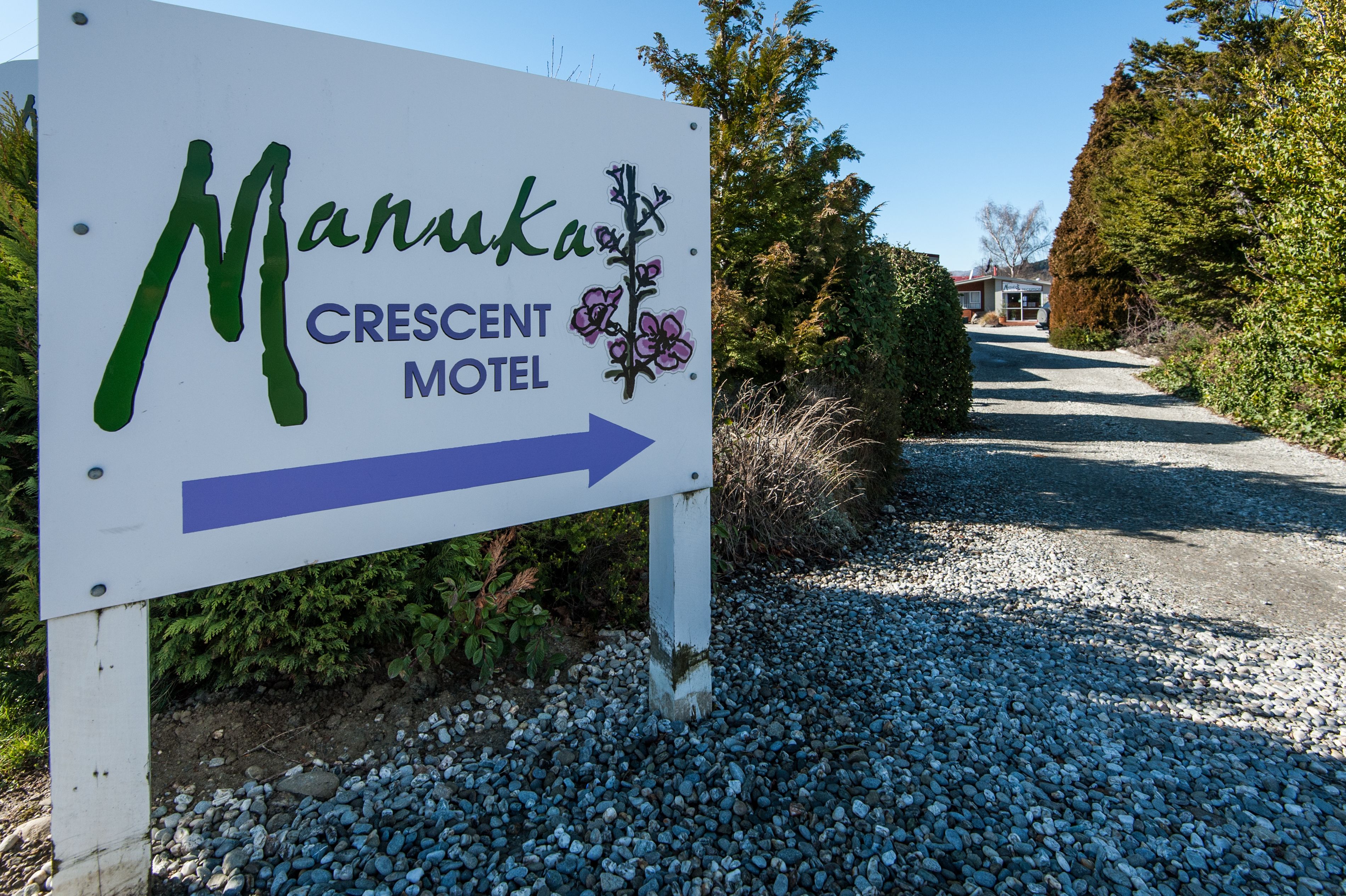 A sign for Manukaka Crescent Motel with directional arrows.