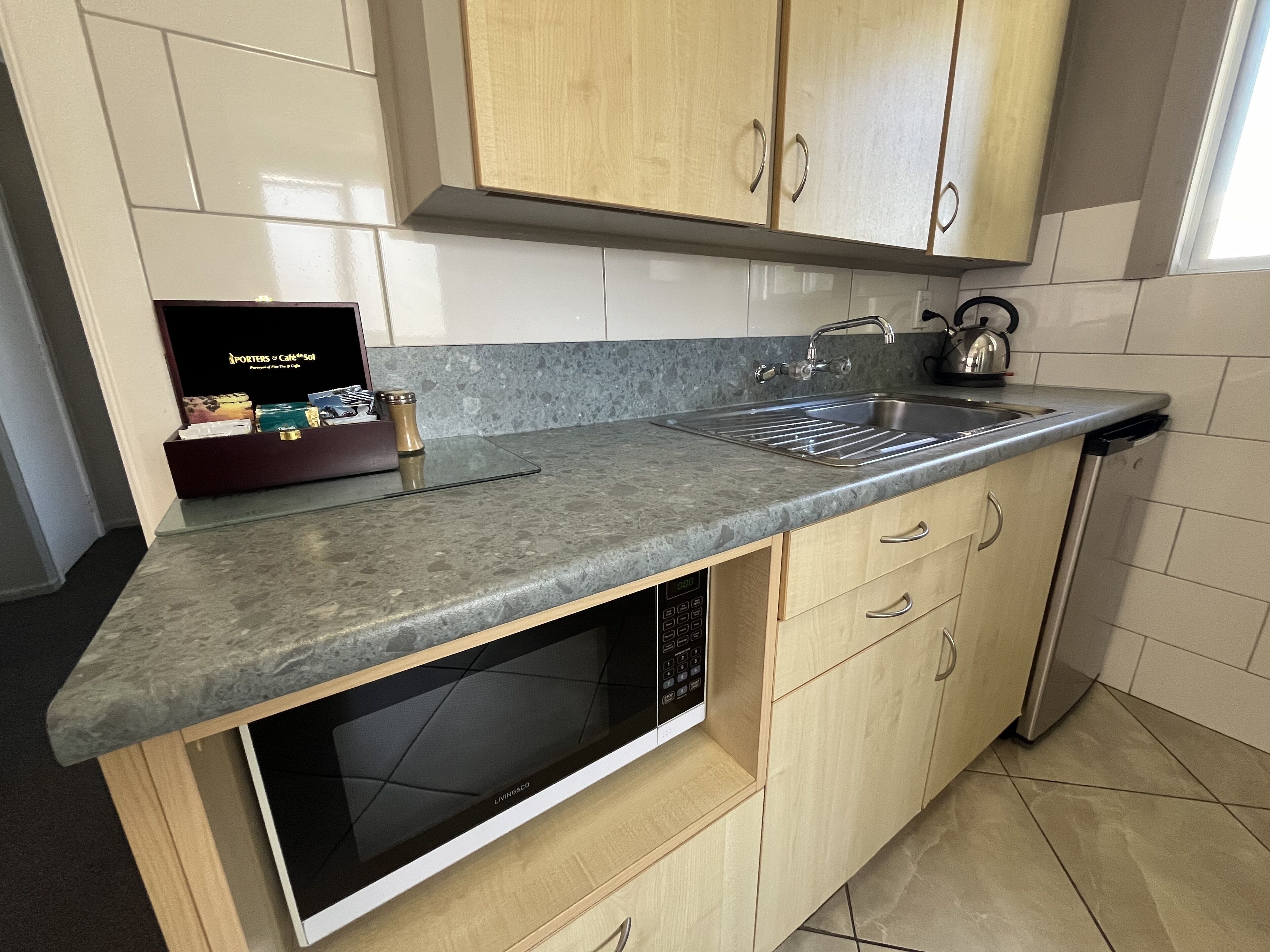 Een keuken met een ingebouwde magnetron, een spoelbak en houten kastjes.