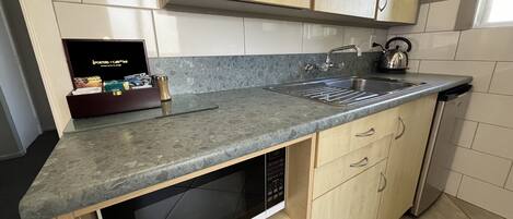 Een keuken met een ingebouwde magnetron, een spoelbak en houten kastjes.