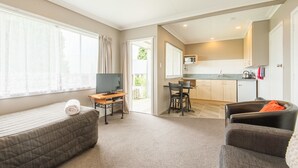 En kompakt bolig med seng, fjernsyn, spiseplads og tekøkken.