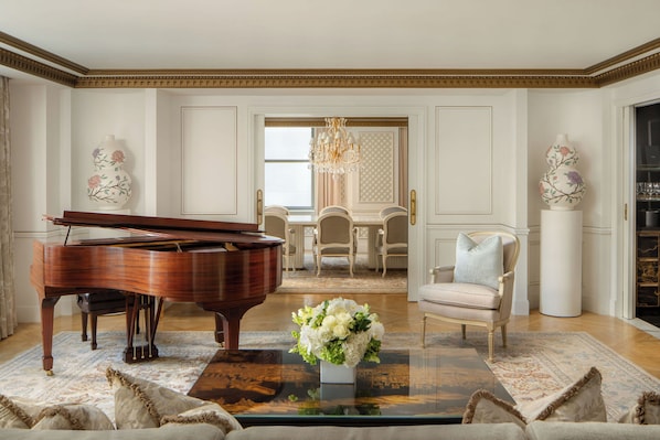 A grand piano, a floral arrangement, and a dining area with a chandelier. - Waldorf Astoria New York (New York)