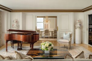 A grand piano, a floral arrangement, and a dining area with a chandelier.