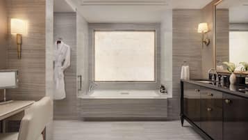 A modern bathroom with a large bathtub, a vanity with a mirror, and a robe hanging on the wall.