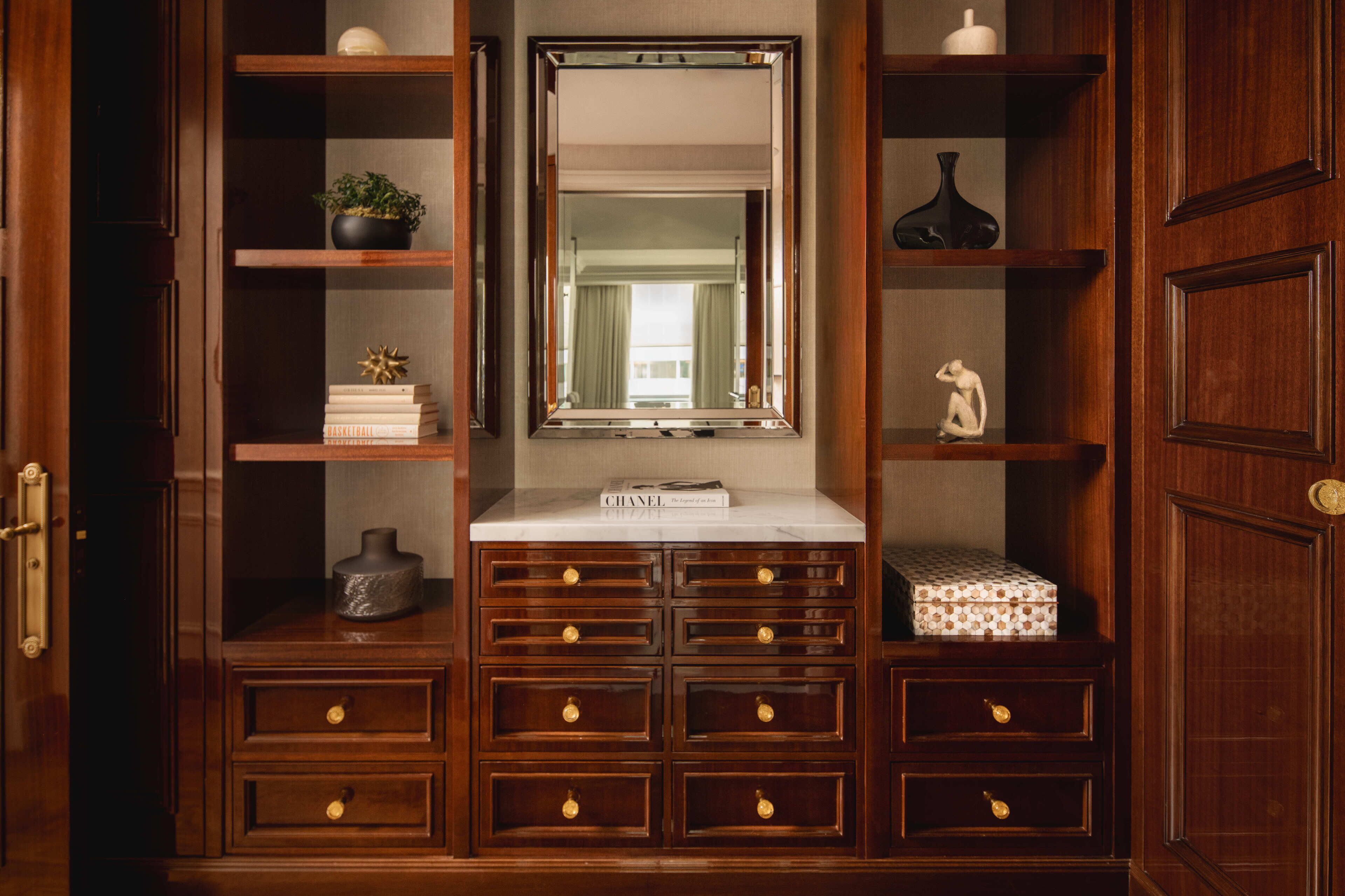A wooden vanity with a mirror, shelves, and drawers.