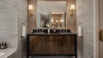 Un baño moderno con tocador de madera oscura, dos lavamanos y un espejo grande.