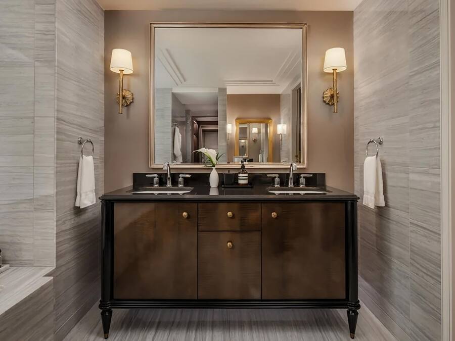 Un baño moderno con tocador de madera oscura, dos lavamanos y un espejo grande.