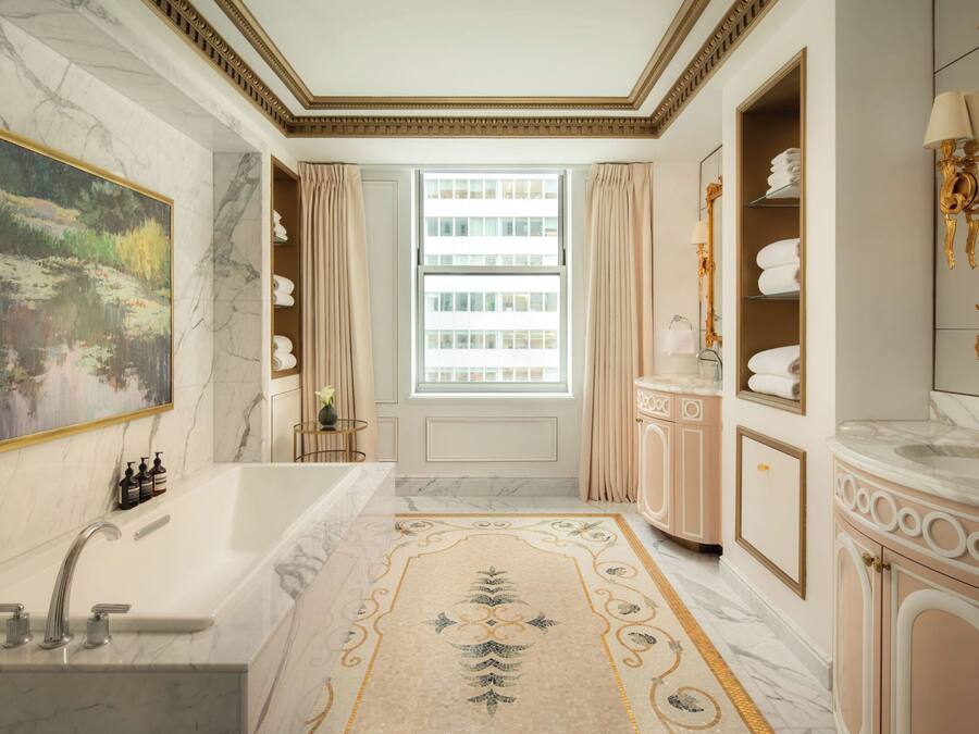 A luxurious bathroom with a marble sink, a large bathtub, and a decorative rug.