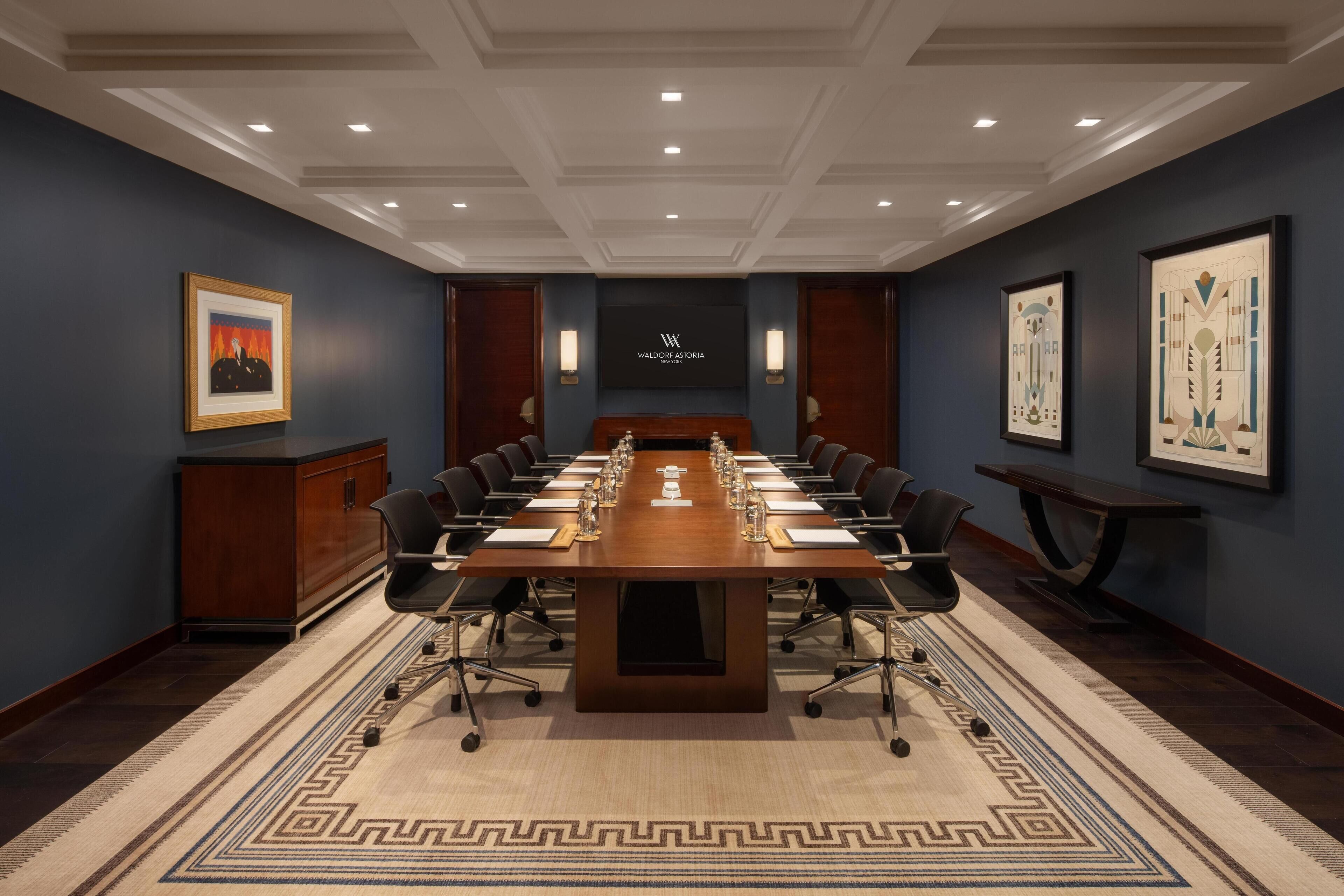 A conference room with a long table, chairs, and a podium.