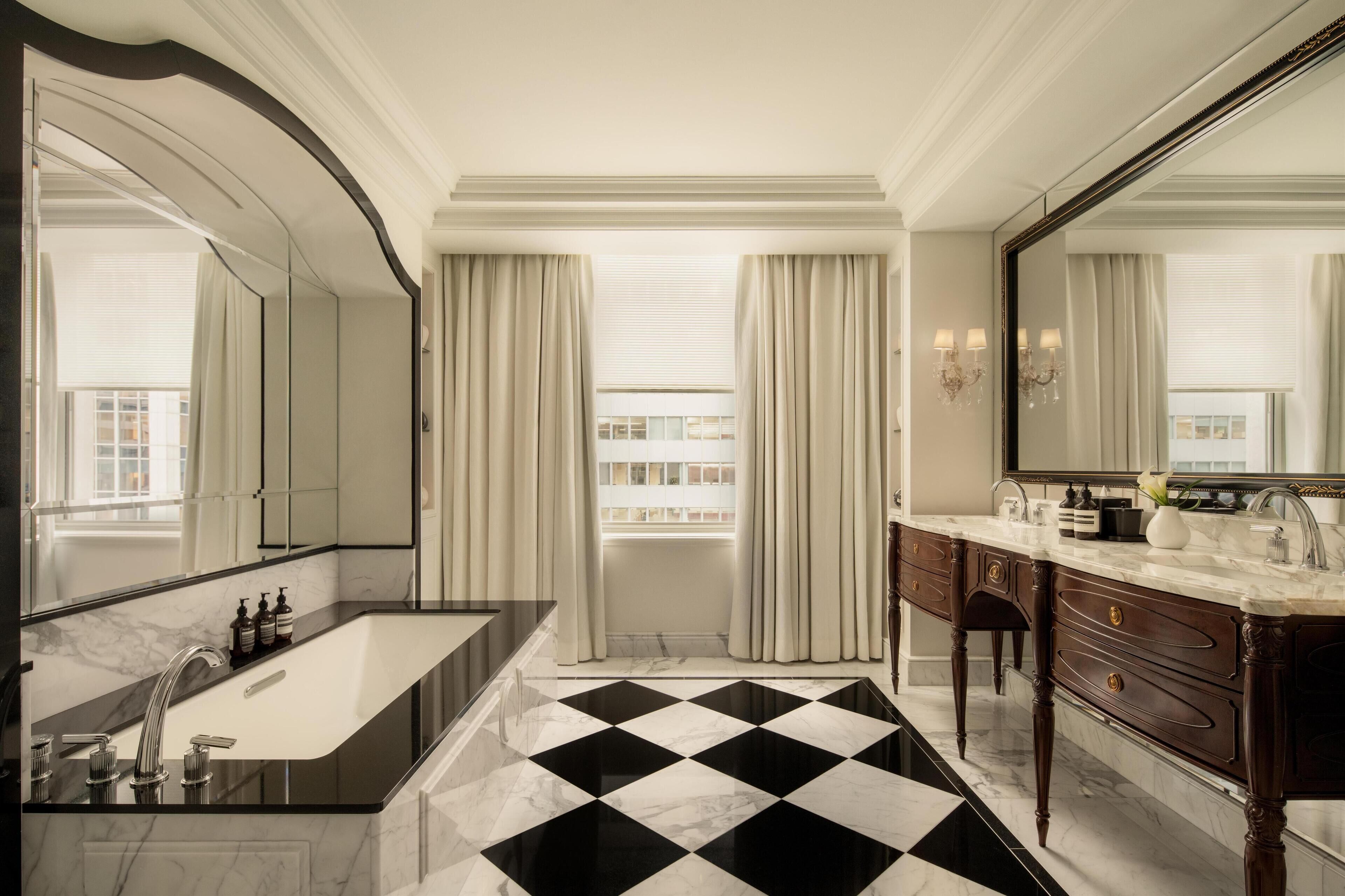 Um banheiro luxuoso com piso xadrez em preto e branco, um espelho grande e um lavatório moderno.