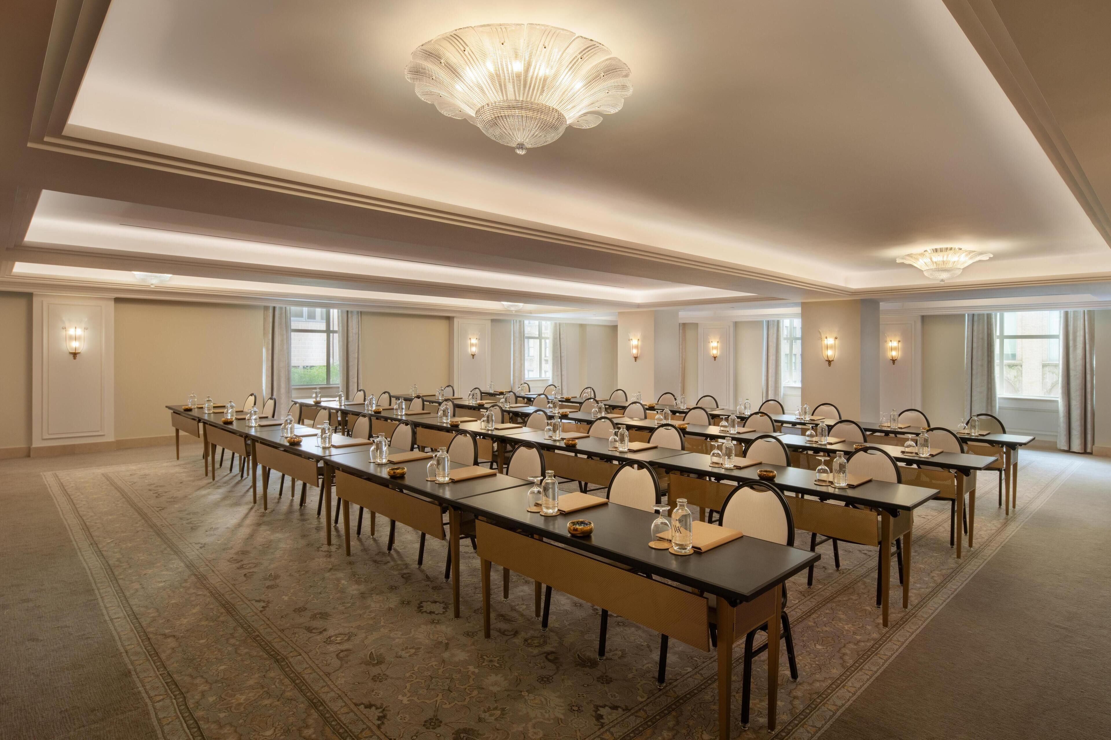 Een ruime congrescentrum met lange tafels, stoelen en een kroonluchter.