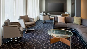 A modern living room with a large flat-screen TV, comfortable seating, and a patterned carpet. - Courtyard New Haven Wallingford (Wallingford)