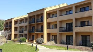 A multi-story residential building with balconies, a landscaped garden, and outdoor seating areas.
