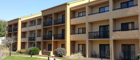 Un edificio residencial de varios pisos con balcones, un jardín ajardinado y zonas de estar al aire libre.