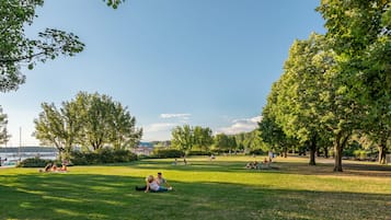 Un parc où l’on peut voir des gens se détendre sur l’herbe, des arbres et un ciel dégagé.
