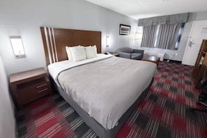 A hotel room with a large bed, a bedside table, a chair, a desk, and a wardrobe. - Quality Inn near Parc Natchitoches (Natchitoches)
