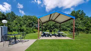A covered picnic area with tables and chairs, a trash can, and a lamp post. - Quality Inn near Parc Natchitoches (Natchitoches)